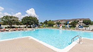 A swimming pool with lounge chairs and a building in the background. - Baywatch I - 201B (Ocean City)