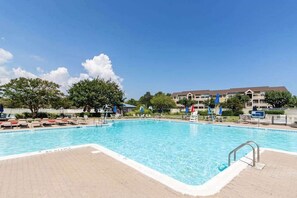 A swimming pool with lounge chairs and a building in the background. - Baywatch I - 201B (Ocean City)