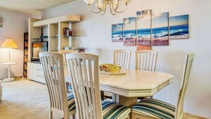 A dining area with a chandelier, striped chairs, and a table with a basket. - Anchorage  304 (Ocean City)