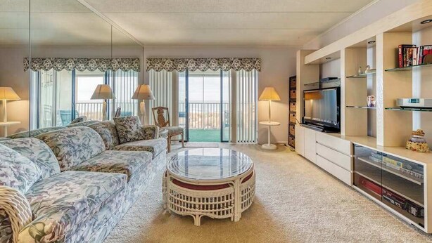 A living room with a sofa, round coffee table, TV, and bookshelves. - Anchorage  304 (Ocean City)
