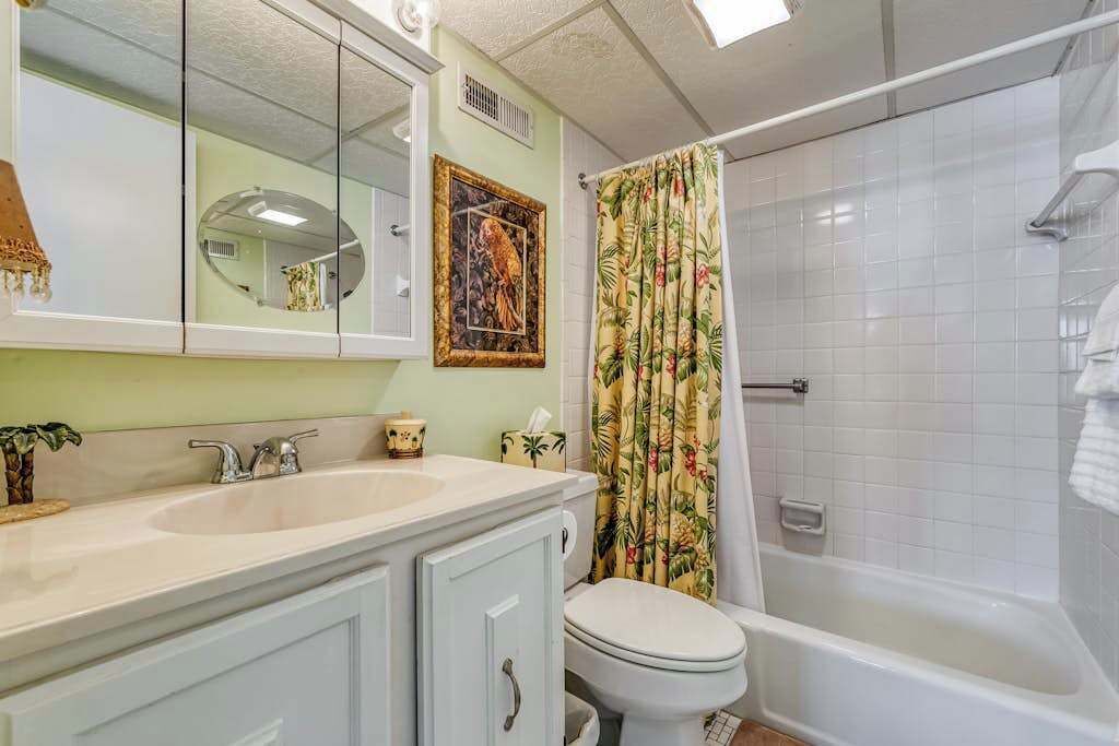 A bathroom with a double sink, toilet, and shower.
