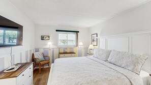 A bedroom with a large bed, bedside tables, a chair, a window, and wall-mounted lamps. - Thunder Island 34B Bay views at Convention Center (Ocean City)