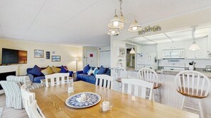 A modern living room with a dining table, sofas, and a kitchen area with white cabinets and a microwave. - Thunder Island 34B Bay views at Convention Center (Ocean City)
