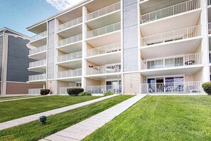 Een meerhoog gebouw met balkons, een plat dak en een geplaveid voetpad.