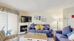 A living room with a fireplace, a television, and a sofa. - Thunder Island 34B Bay views at Convention Center (Ocean City)