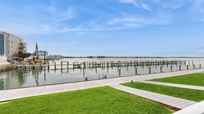 A waterfront promenade with a wooden deck, grassy areas, and a construction site with a CAT excavator. - Thunder Island 34B Bay views at Convention Center (Ocean City)