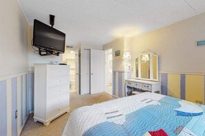 Een slaapkamer met een bed, een kaptafel, een televisie en een spiegel.