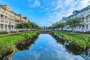 A canal with a stone bridge, lined with multi-story buildings with balconies, and a clear sky. - Sunset Island - 1 Beachside Mews (Ocean City)