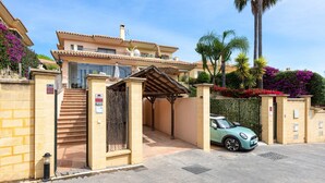 A two-story building with a gated entrance, a covered outdoor seating area, and a parked car.