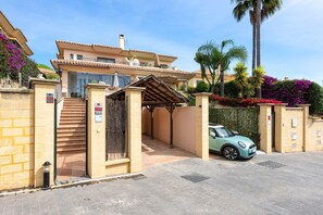 A two-story building with a gated entrance, a covered outdoor seating area, and a parked car. - Holiday Home 'Villa Flamencos' with Mountain Views, Wi-Fi and Air Conditioning (Mijas)