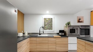 A modern kitchen with wooden cabinets, a stainless steel sink, a coffee maker, and a microwave.