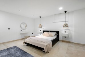 A modern bedroom with a bed, bedside tables, a mirror, and pendant lights.