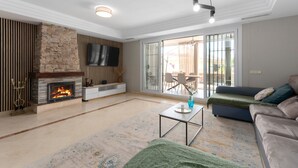 A modern living room with a fireplace, a flat-screen TV, a sofa, and a coffee table.