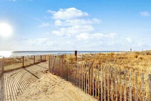Ein Strand mit Holzfence, sandigem Weg und Blick auf den Ozean.