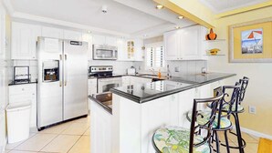 Una cocina moderna con armarios blancos, una isla central y taburetes de bar.