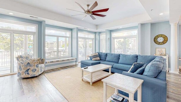 Un salón amplio con un sofá azul, una mesa de centro y un sillón con motivos náuticos.