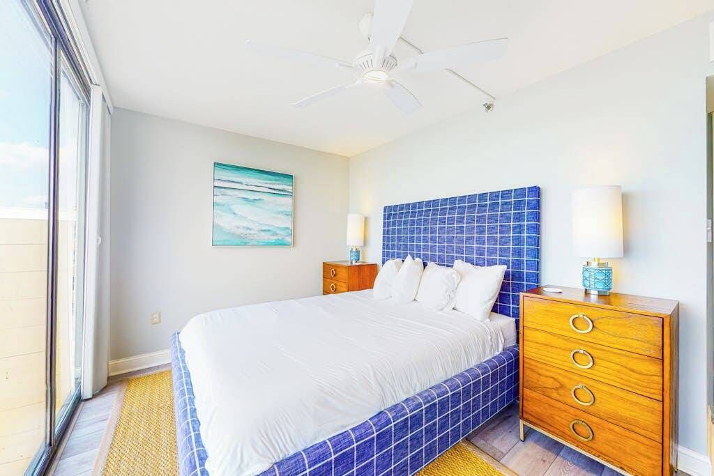 A bedroom with a bed, a nightstand, a ceiling fan, and a window.
