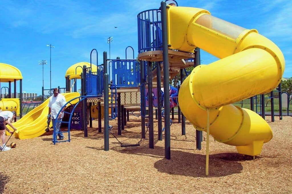 Un parc infantil amb tobogans grocs i elements per escalar.