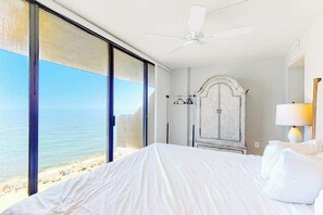 Ein Hotelzimmer mit Bett, Deckenventilator, Kleiderschrank und Blick auf den Strand.