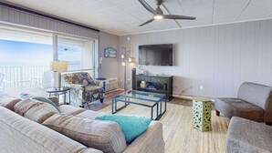 A living room with a sofa, armchair, coffee table, and a television. - Calypso 705 (Ocean City)