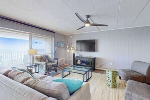 A living room with a sofa, armchair, coffee table, and a television. - Calypso 705 (Ocean City)