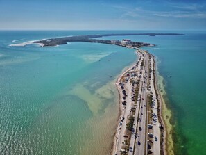 Luftaufnahme einer Küstenstraße mit Strand und Gebäuden in der Ferne.