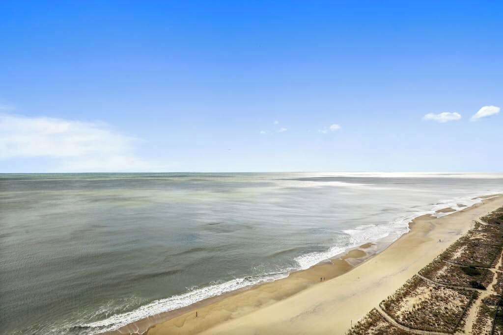A beach with a clear sky, a sandy shore, and a calm sea.