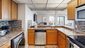 A modern kitchen with wooden cabinets, a dishwasher, a built-in oven, and a granite countertop.