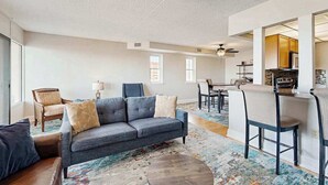 A living room with a sofa, chairs, a coffee table, and a kitchen area with a dining table and chairs.