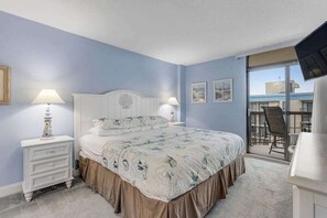 Ein Schlafzimmer mit einem Bett, zwei Nachttischen mit Lampen, einer Kommode und einem Balkon mit einem Stuhl.