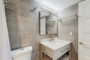 Moderni kylpyhuone, jossa on wc, pesuallas, peili ja pyyheteline.