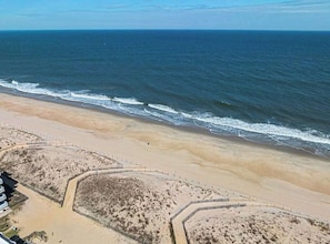 Una playa con orilla arenosa, una cerca de madera y una vista despejada del océano.
