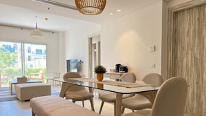 A modern dining area with a glass table, cushioned chairs, and a bench. - Fouka North Coast SA-4B-203 (Marsa Matrouh)