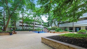 Un patio con árboles, una fuente y un edificio de varios pisos.