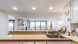 Una cocina moderna con una isla central, lavavajillas integrado y un amplio ventanal con vistas a la ciudad.
