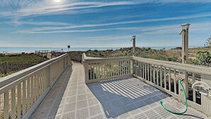 A wooden deck with a metal railing overlooking a beach. - Third-floor condo in oceanfront building with balcony, pool & beach access (Ocean City)