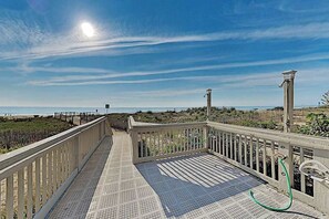 Une terrasse en bois avec une rambarde en métal donnant sur une plage.