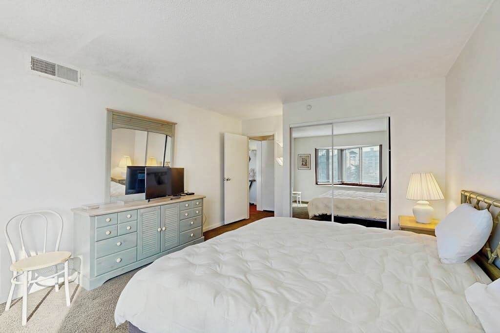 Un dormitorio con cama, cómoda, televisión y espejo.