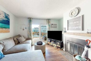 Ein Wohnzimmer mit Sofa, Fernseher, Kamin und Blick ins Freie.