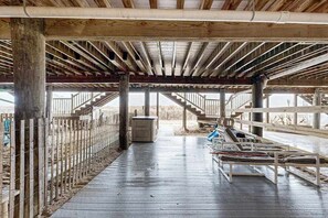 An open wooden structure with a staircase, a covered seating area with cushions, and a fenced perimeter. - Ocean-view townhome with easy beach access & large deck (Ocean City)