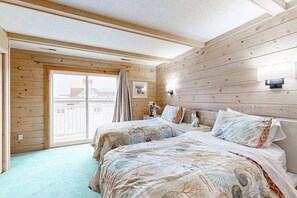 A room with two beds, wooden walls, a large window, and a view of buildings outside. - Ocean-view townhome with easy beach access & large deck (Ocean City)