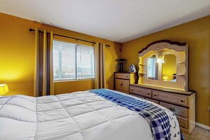 A hotel room with a bed, a dresser, a mirror, and a window with curtains. - Updated condo with seasonal pool, 2 blocks to the beach & Northside Park (Ocean City)
