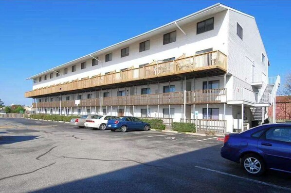 Ein mehrgeschossiges Motel mit flachem Dach, Balkonen und einem Parkplatz mit mehreren Autos.