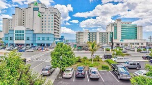 Een hotel met meerdere verdiepingen, een parkeerplaats en een heldere lucht.