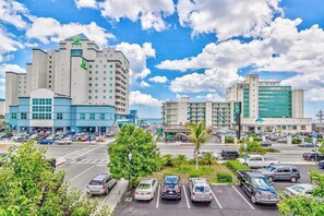 A hotel with multiple floors, a parking lot, and a clear sky. - Peek-a-Boo Oceanview Condo with Shared Pool & Prime Location 1 Block from Beach (Ocean City)