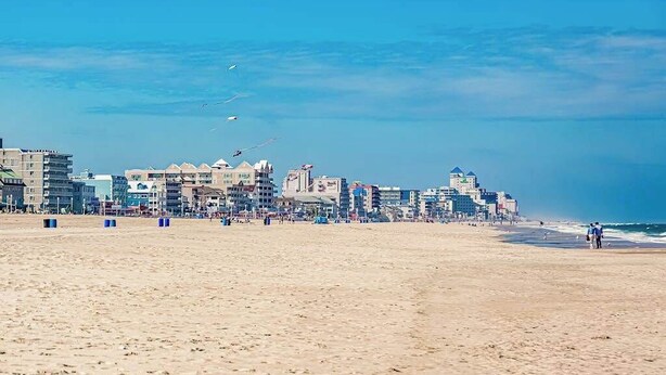 Een strand met gebouwen op de achtergrond.