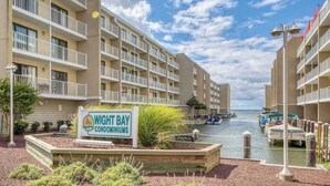 Un complesso condominiale sul lungomare con numerosi balconi, un porto turistico e un cartello con la scritta 'Wight Bay Condominiums'.