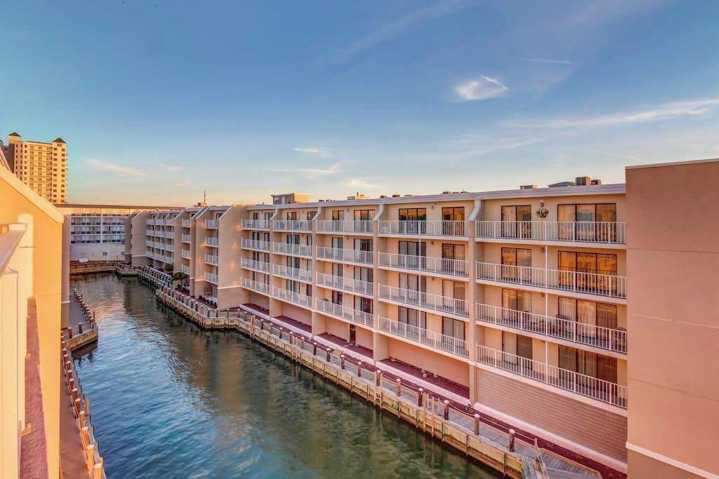 Un hotel a più piani con balconi, un canale d'acqua e cielo sereno.