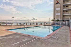 A swimming pool with a view of the ocean, a fenced deck area, and a building with a sailboat logo. - Wight Bay North 544 (Ocean City)