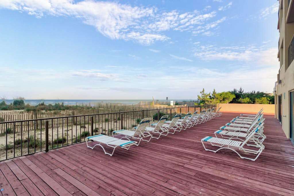 Una terrazza in legno con lettini che si affaccia su una spiaggia.